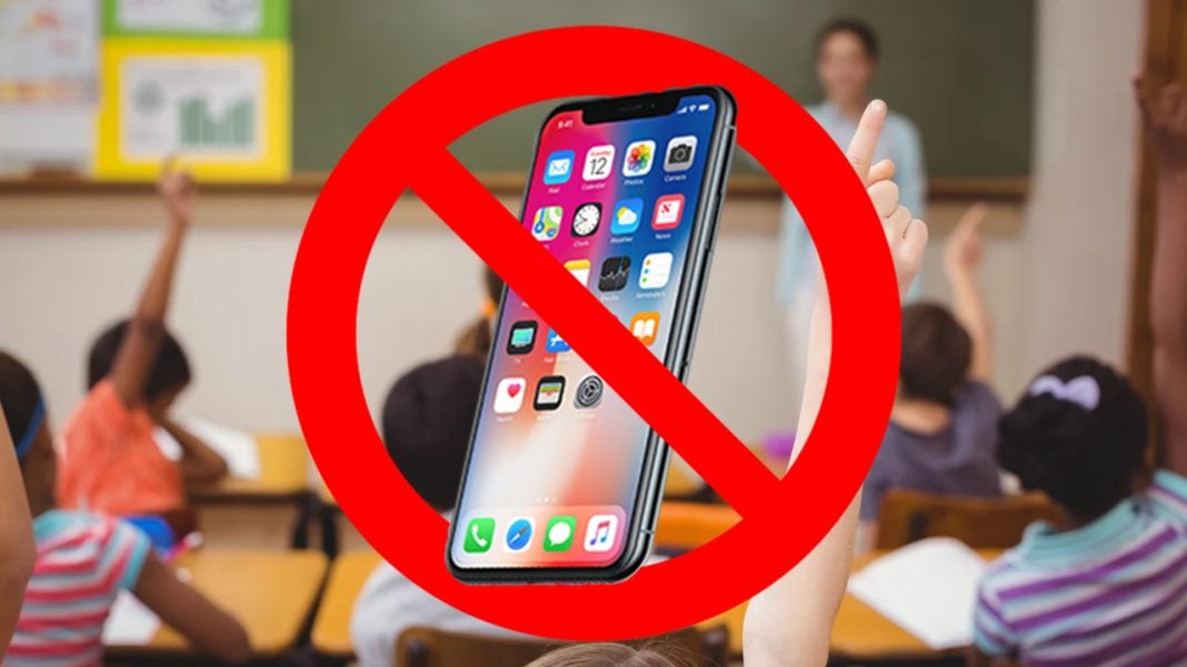 A phone with a classroom in the background being crossed out by a large red circle with a red line through it.