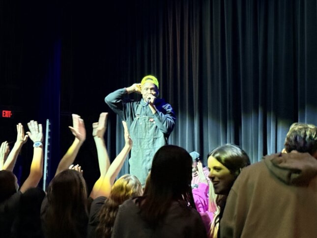 Look at all the fun the crowd is having. Morse is rapping one of his songs. The crowd his swaying and clapping their hands in the background.